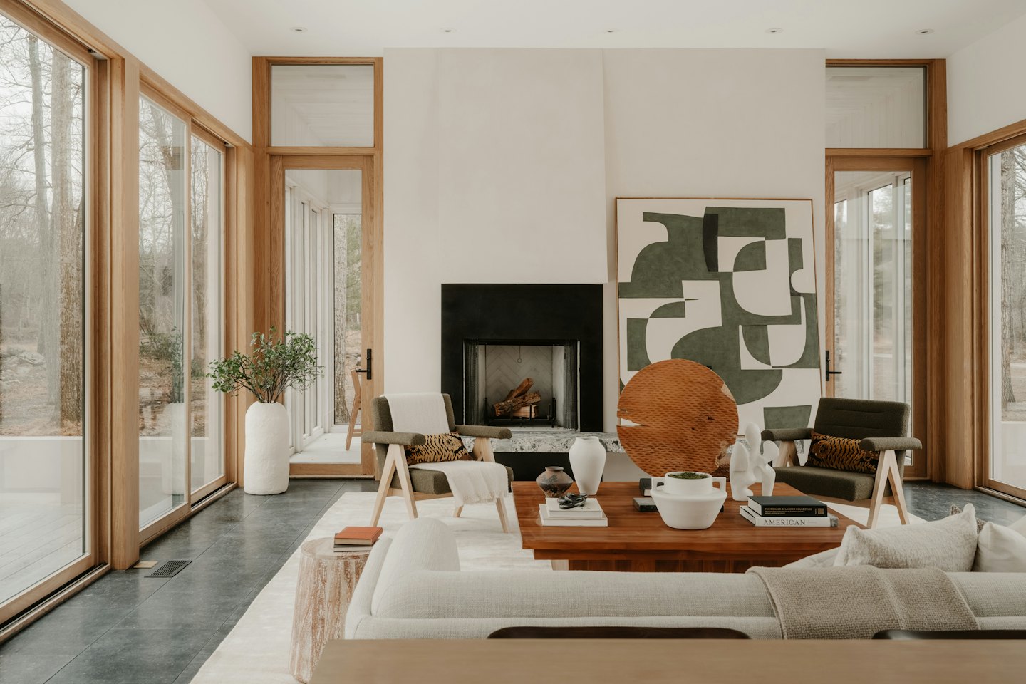 Sala de estar moderna con grandes ventanales y chimenea negra.