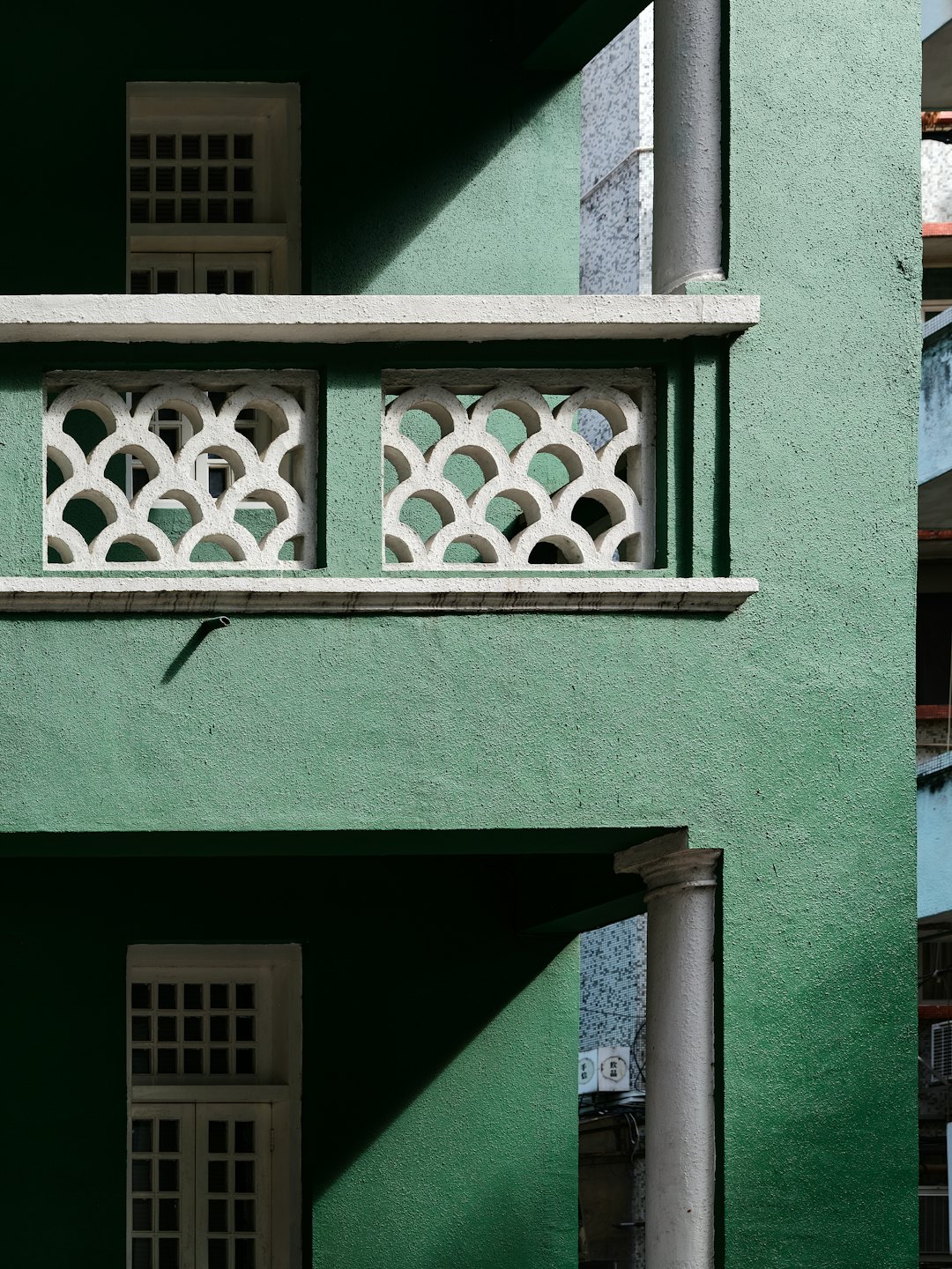 Paredes verdes texturizadas con balaustrada y marcos de ventana blancos.