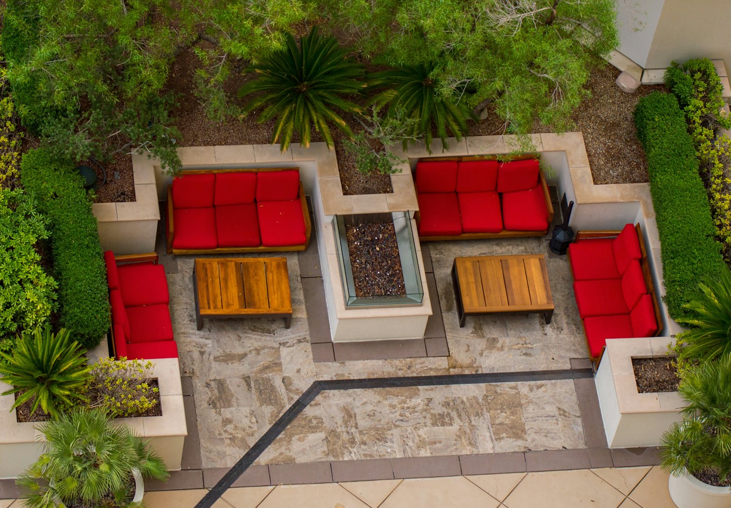 Sofás rojos con cojines rodean una fogata en un patio.