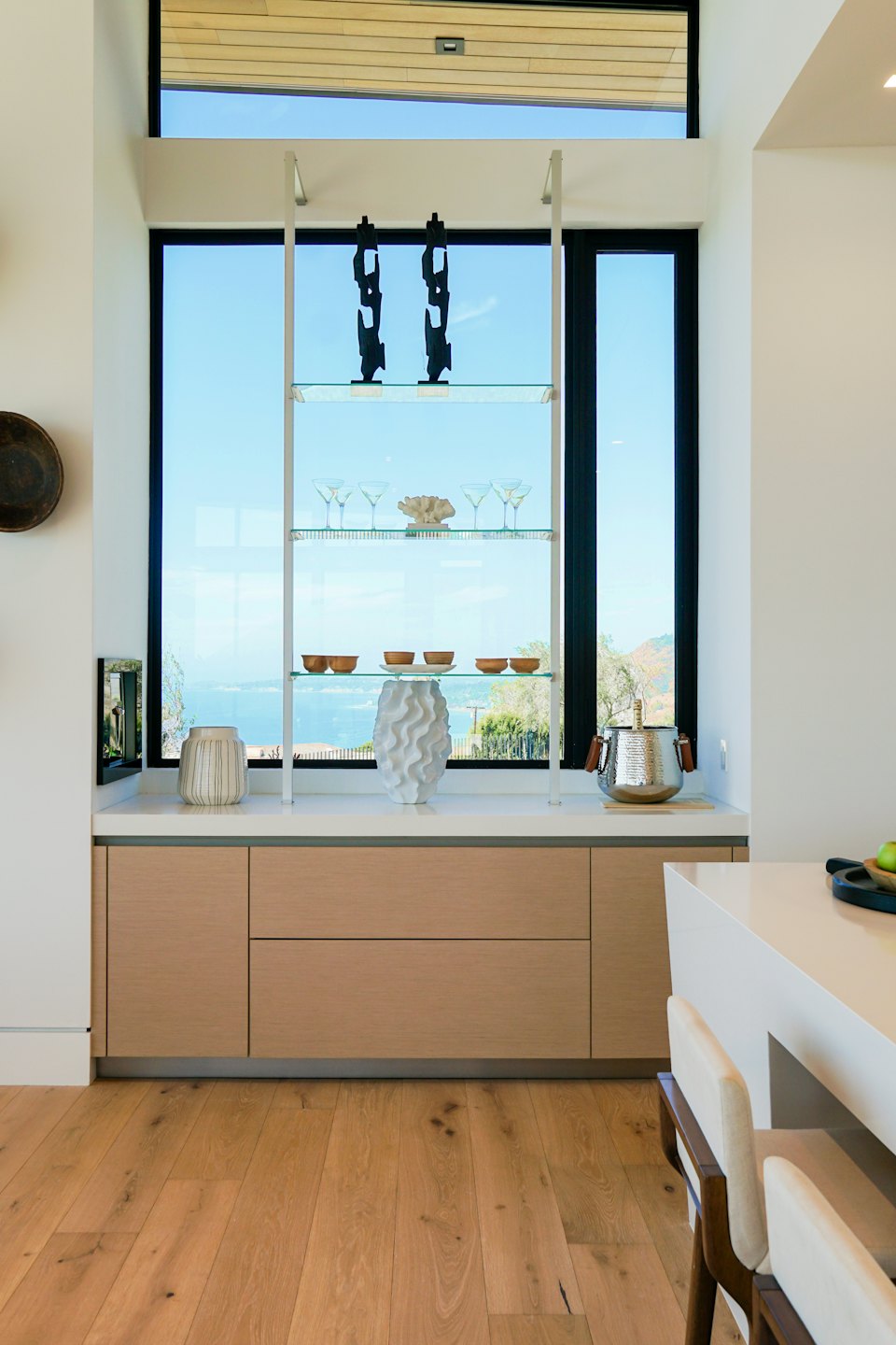 Modernos gabinetes de cocina de madera con estantes de exhibición con vista a montañas y agua.