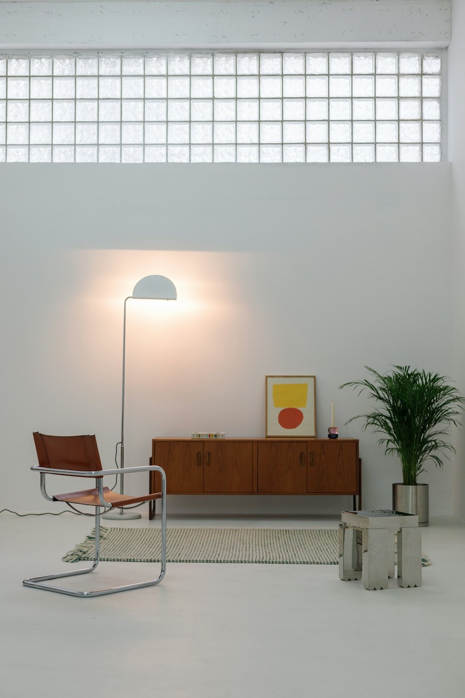 Habitación minimalista moderna con sillón de cuero y planta de interior.