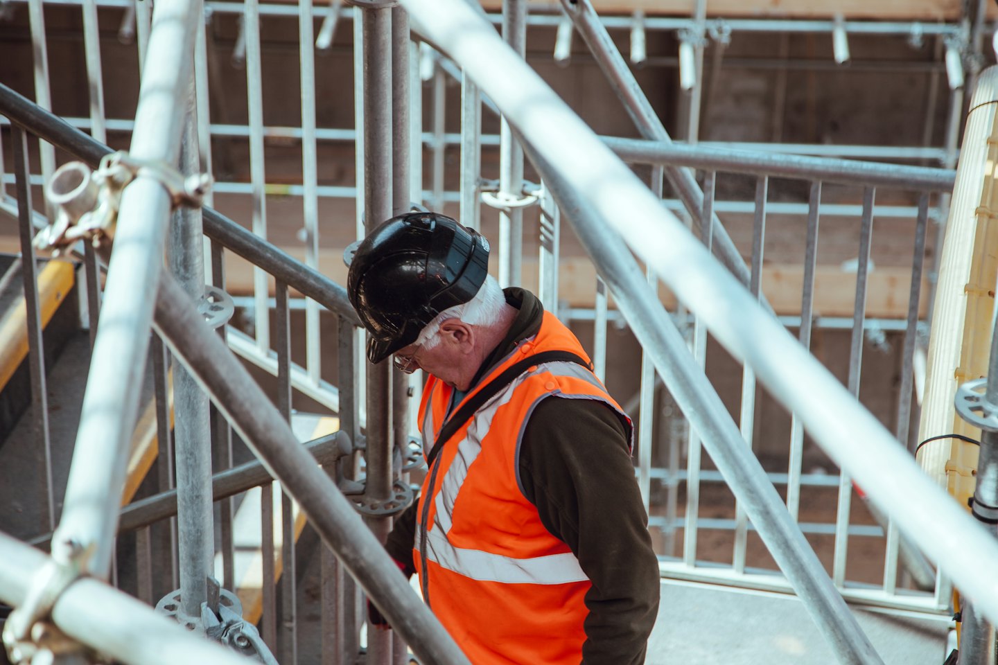 Obrero de la construcción con casco inspecciona andamios en obra.