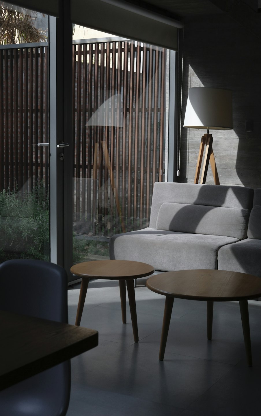 Salón minimalista con sofá gris y mesas de madera.