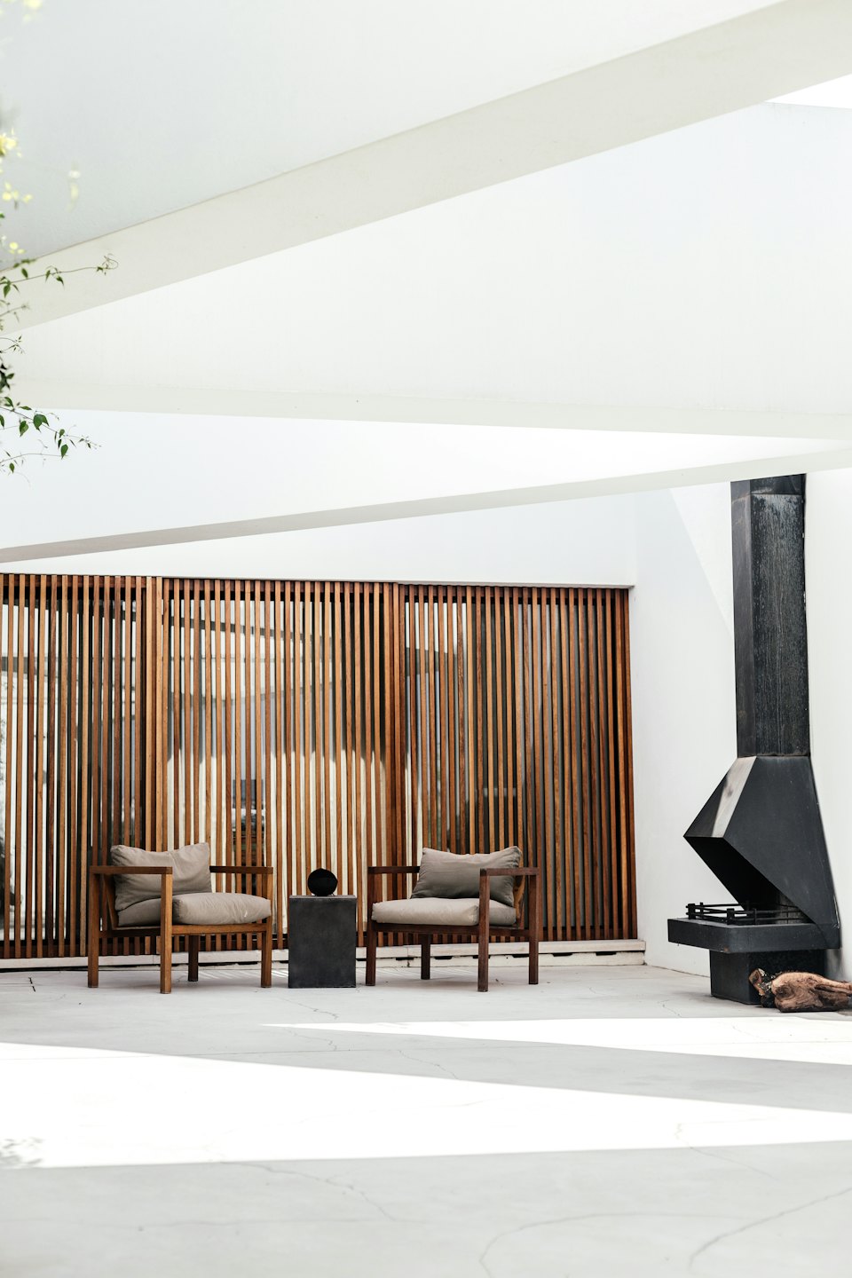 Dos sillas modernas y mesa auxiliar en un patio minimalista.