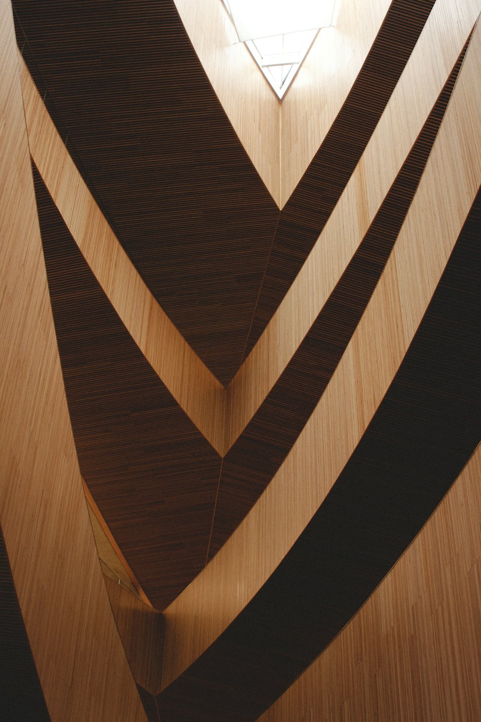 Paneles de madera geométricos en una pared moderna que conducen a una claraboya.
